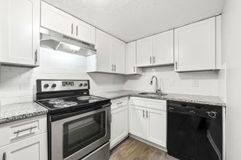 Upgraded kitchen with white cabinets and stainless steel appliances at Pines at Lawrenceville Apartments in GA 30033