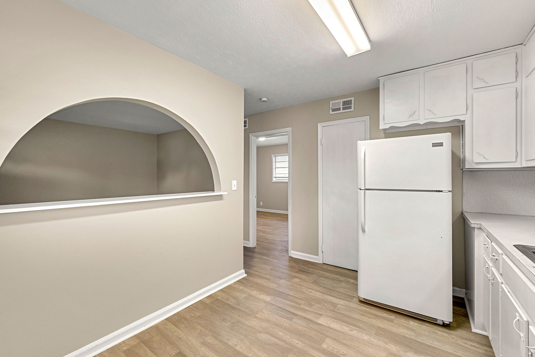 A kitchen with a white refrigerator and wooden floors.