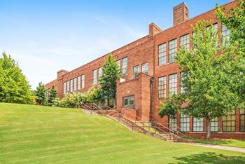 a large brick building with a green lawn and trees at Crogman School Lofts, Atlanta, 30315