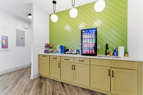 A kitchen with a green wall and wooden cabinets.