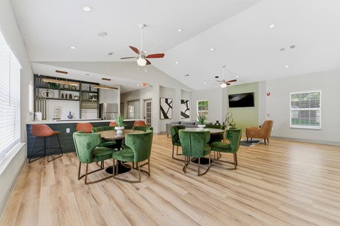 A dining room with a table set for six with green chairs.