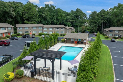 A swimming pool is surrounded by a black fence and a small pavilion.