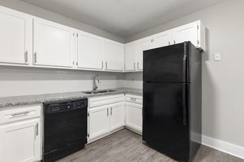 an empty kitchen with white cabinets and a black refrigerator at Ridgewood Apartments, Lawrenceville, 30045