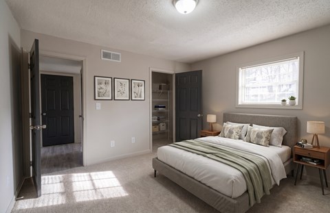 A bedroom with a bed, nightstand, and a window.