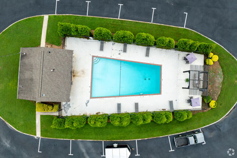 A swimming pool surrounded by a grassy area and a concrete wall.