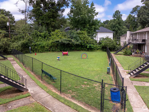 A backyard with a fence, a slide, and a trash can.