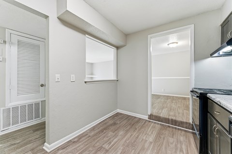 A kitchen area with a white door, a window, and a black stove top oven.