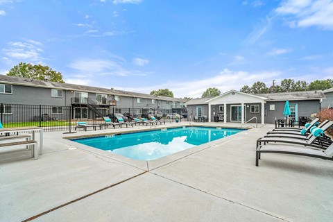 A swimming pool surrounded by lounge chairs and a building in the background.