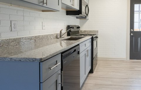 A kitchen with a marble countertop and a stainless steel dishwasher.