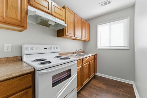 A kitchen with a white stove and wooden cabinets.