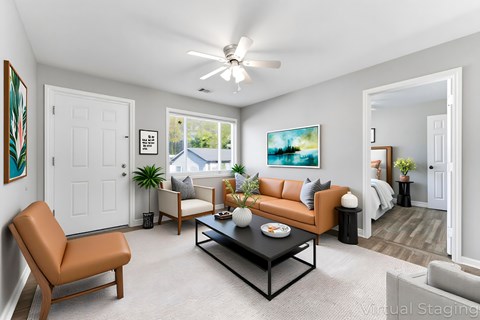 A living room with a brown leather chair, a black coffee table, and a painting on the wall.
