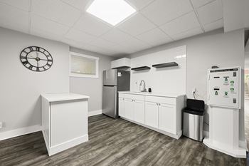 Clubhouse kitchen with white cabinets and a clock on the wall at Gardens at Washington Park, Atlanta, GA, 30314