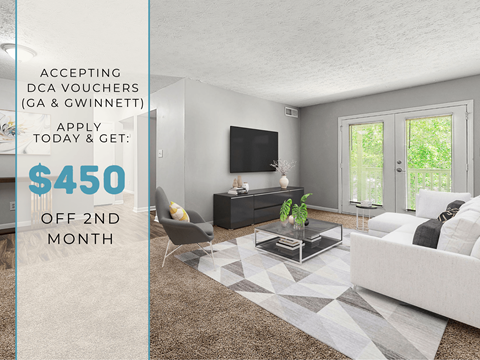 A living room with a grey sofa, a black TV, and a glass coffee table with a plant on it.