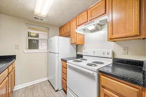 A kitchen with a white stove top oven and a white refrigerator.