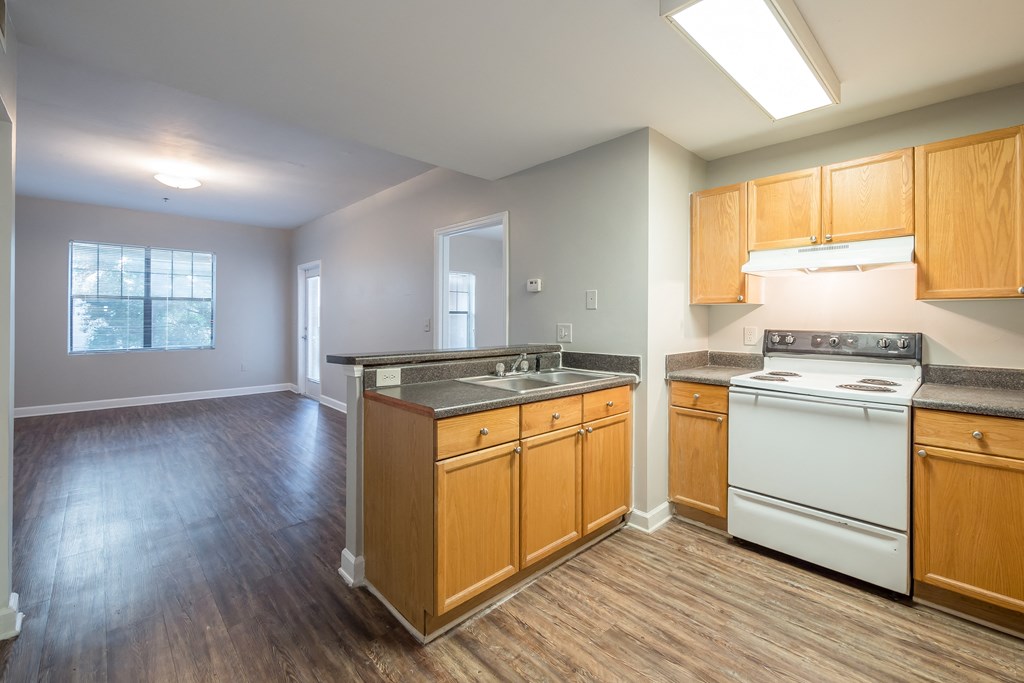 an empty kitchen with wood flooring and white appliances at Crogman School Lofts in Atlanta, GA