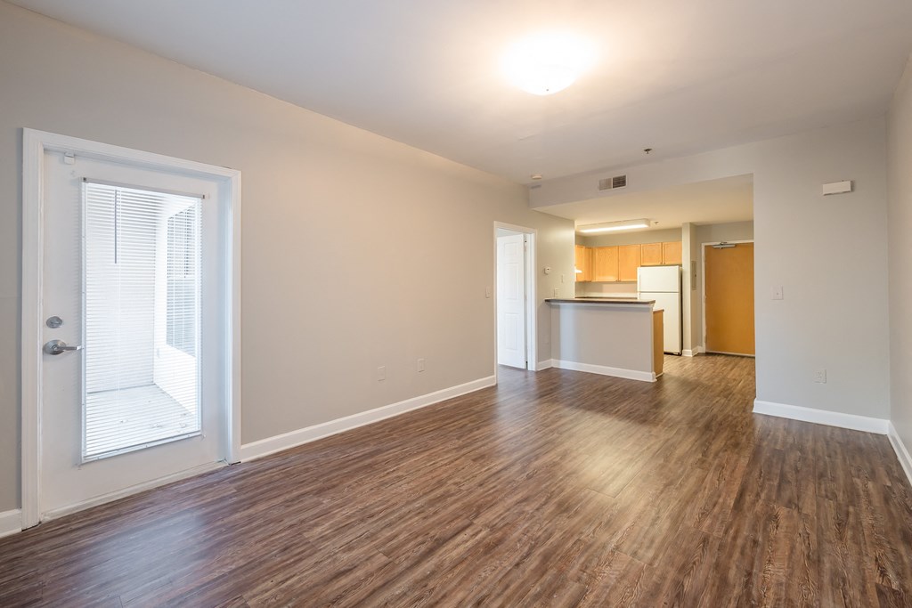 the living room and kitchen of an apartment with wood flooring and a large window at Crogman School Lofts, Atlanta, 30315