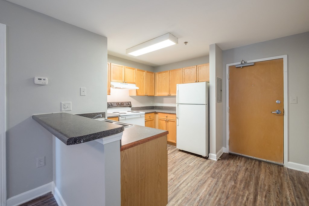an empty kitchen with white appliances and wooden cabinets at Crogman School Lofts, Georgia