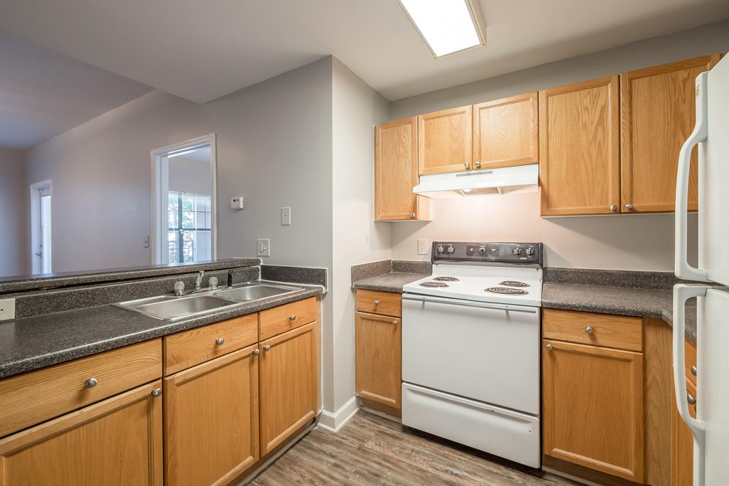 an empty kitchen with white appliances and wooden cabinets at Crogman School Lofts, Georgia