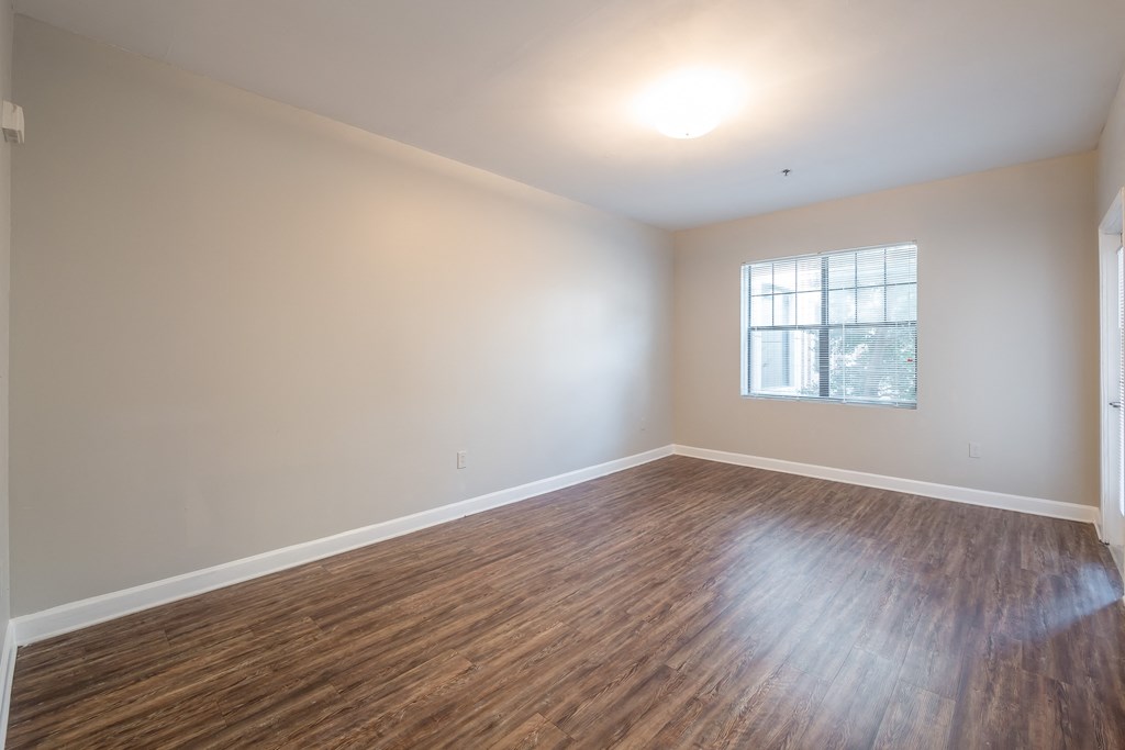 an empty living room with wood floors and a window at Crogman School Lofts in Atlanta, GA