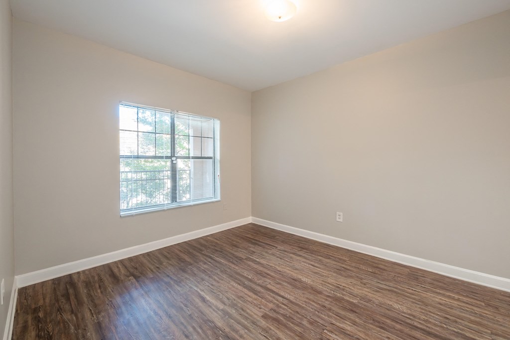 an empty living room with wood floors and a window at Crogman School Lofts, Atlanta, 30315