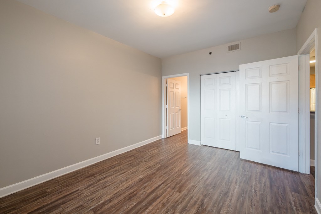 an empty living room with wood flooring and white doors at Crogman School Lofts, Atlanta, GA