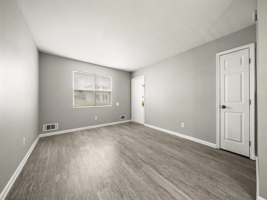 an empty bedroom with a white door and wood floors