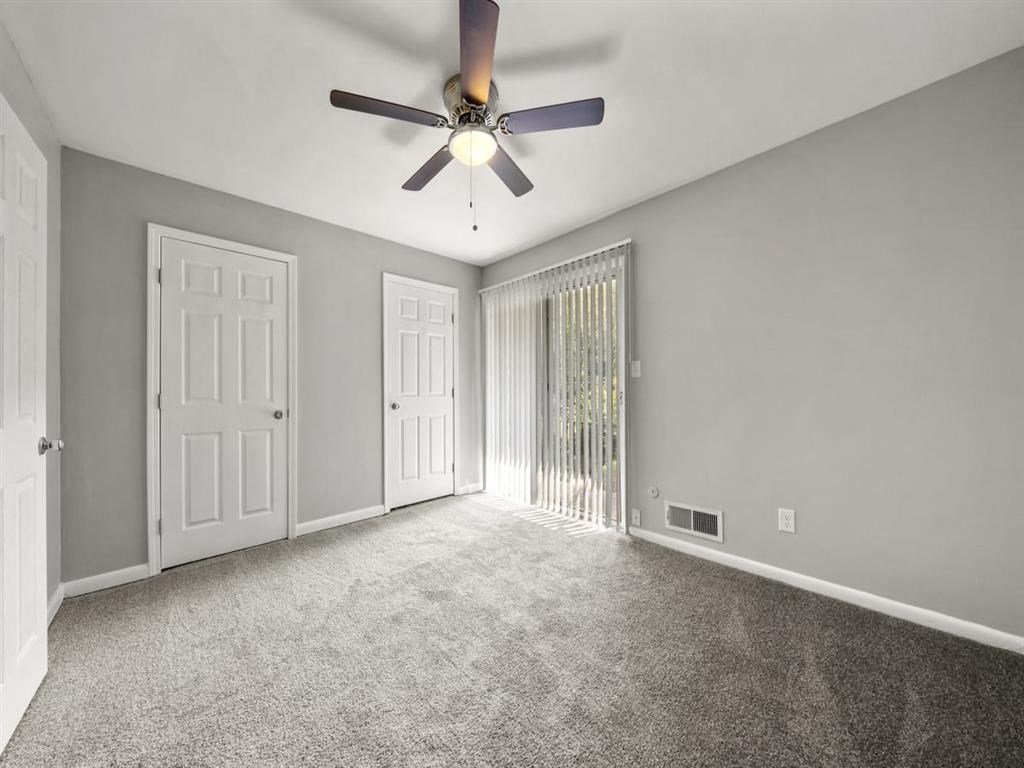 an empty living room with a ceiling fan and a window