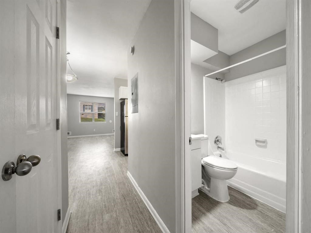 a white bathroom with a toilet and a bath tub