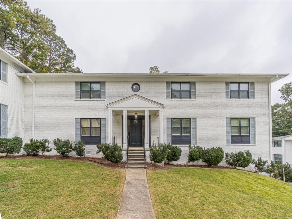 a white brick house with black windows and a lawn