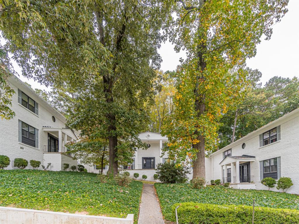 the exterior of a white house with trees and a walkway