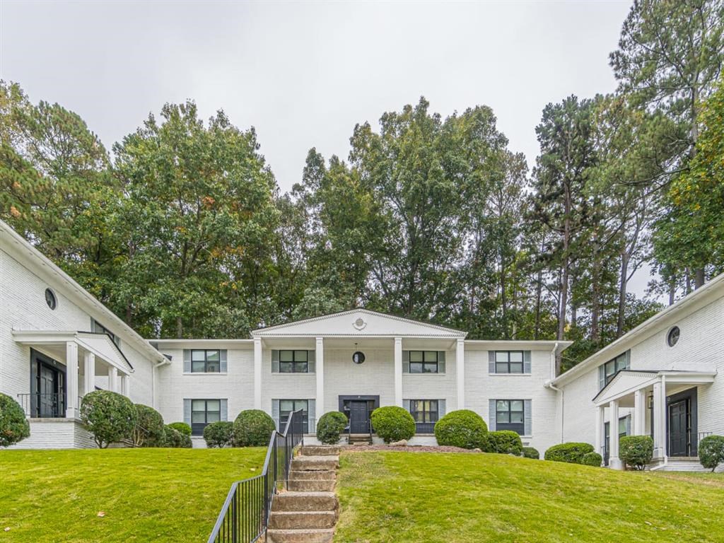 a white house with a green lawn and trees