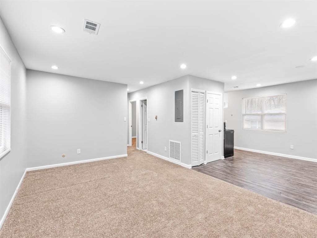 the living room is empty of furniture and has white walls and a carpet