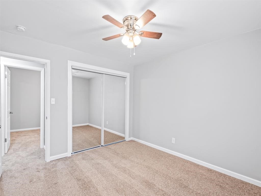 a bedroom with a ceiling fan and a mirrored closet