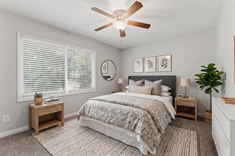 A bedroom with a bed, nightstands, and a ceiling fan.