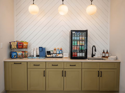 A kitchen with green cabinets and a white wall with a fridge on top.