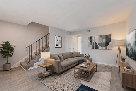 A living room with a couch, coffee table, and a plant.