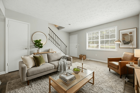 A living room with a couch, a chair, a coffee table, and a plant.