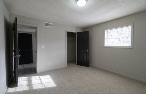 A room with a black door and a window with a newspaper on it.