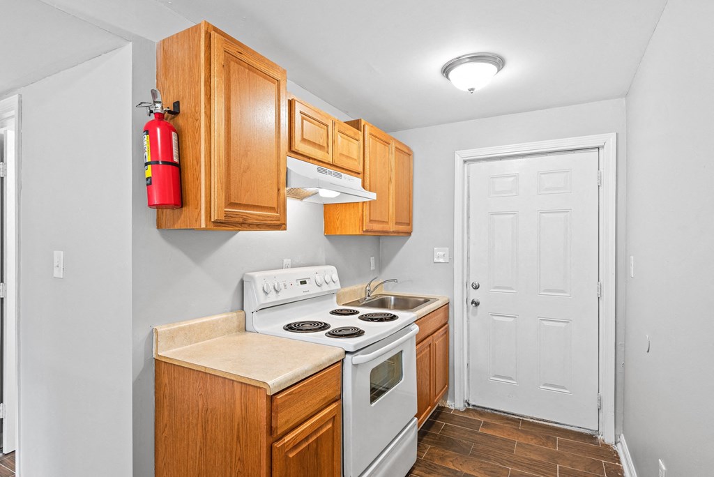 a kitchen with wood cabinets and white appliances at Gardens at Washington Park, Georgia , 30314