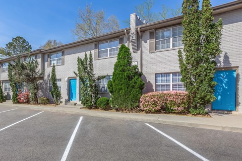 A parking lot in front of a grey building with blue doors.