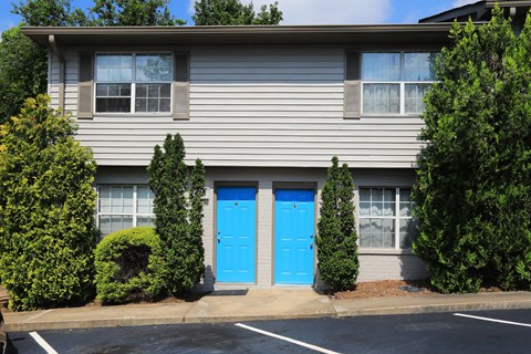 A grey building with a blue door and windows.