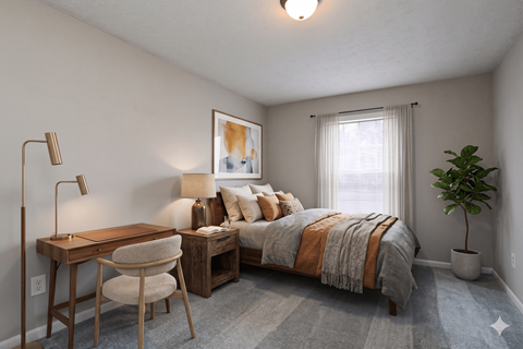 A bedroom with a bed, desk, chair, and a potted plant.