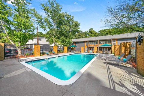 A large outdoor swimming pool surrounded by trees and a building.