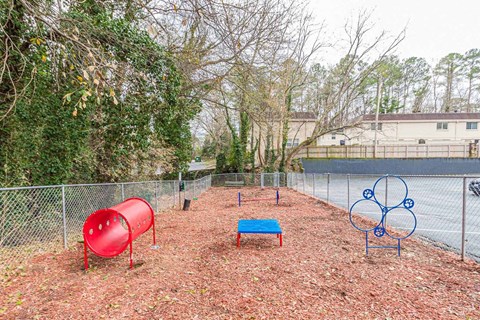 A playground with a red slide, a blue bench, and a blue metal structure.
