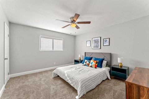A bedroom with a bed, nightstand, and a ceiling fan.