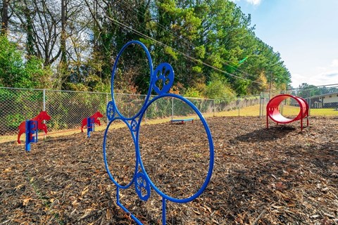 A playground with a blue metal structure and red and blue slides.