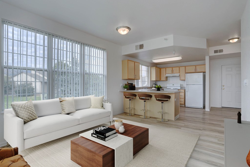 A white couch sits in a living room with a kitchen in the background.
