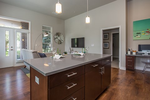 A kitchen with a large island and brown cabinets.