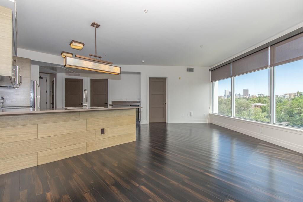 A modern kitchen with wooden floors and a large window.