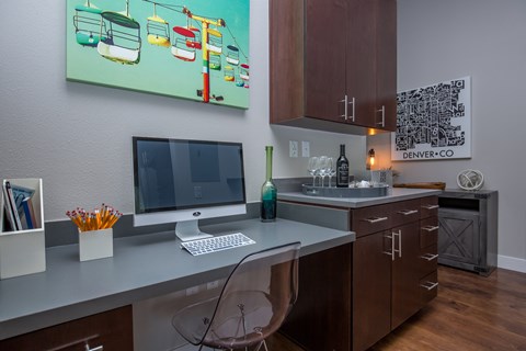 A modern kitchen with a desk and a computer.
